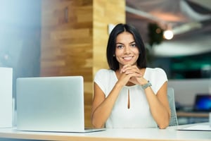 Portrait-of-a-cheerful-businesswoman-sitting-at-the-table-in-office-and-looking-at-camera (1)